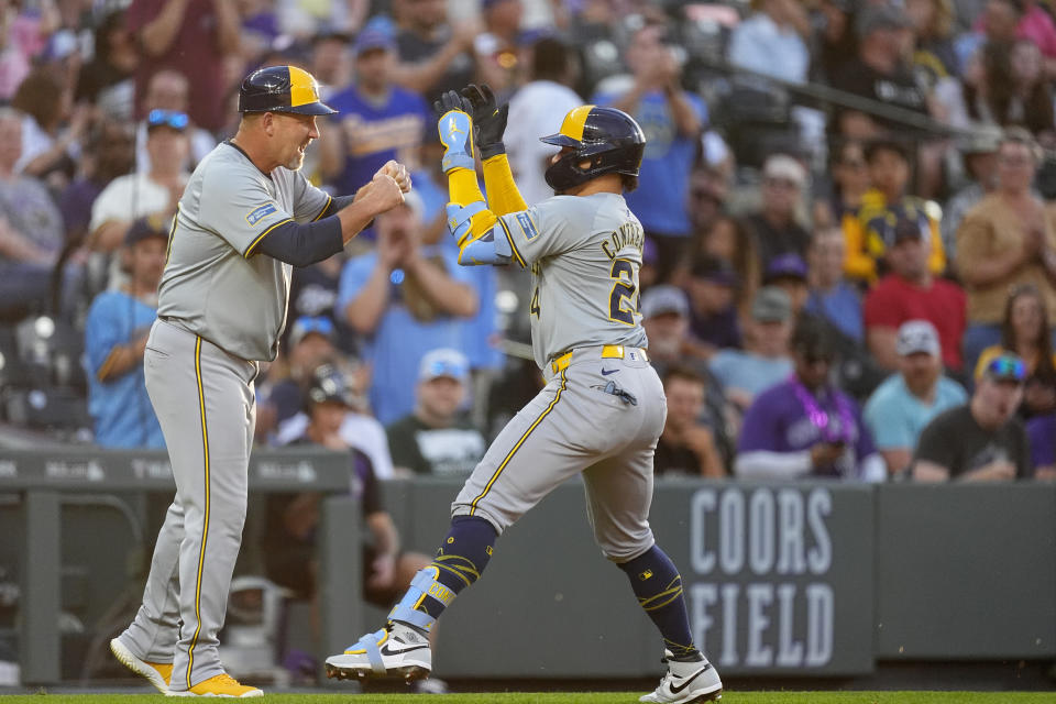 Milwaukee Brewers third base coach Jason Lane, left, congratulates William Contreras, right, who circles the bases after hitting a solo home run off Colorado Rockies starting pitcher Austin Gomber in the fifth inning of a baseball game Monday, July 1, 2024, in Denver. (AP Photo/David Zalubowski)