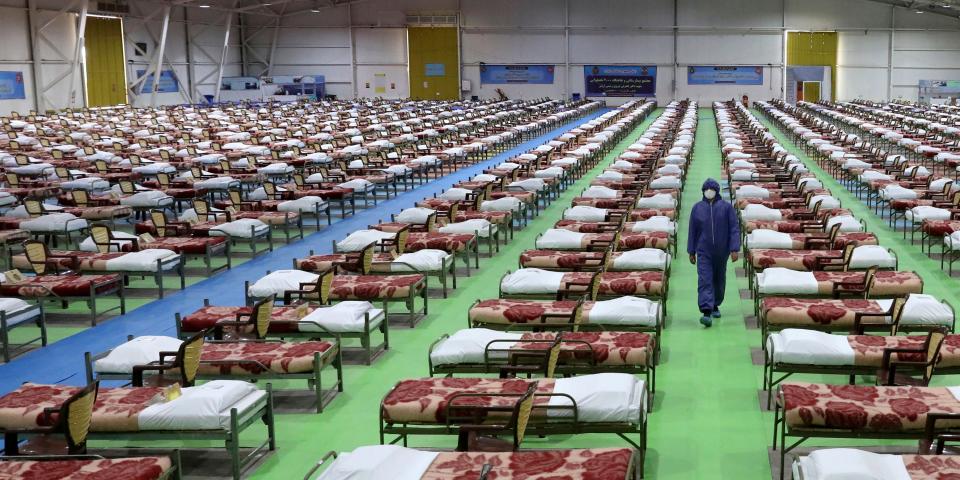 A member of the Iranian army walks past rows of beds at a temporary 2,000-bed hospital for COVID-19 coronavirus patients set up by the army at the international exhibition center in northern Tehran, Iran, on Thursday, March 26, 2020. (AP Photo/Ebrahim Noroozi)