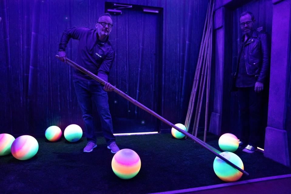 Founder and CEO of Level 99, Matthew DuPlessie, (with publicist Adam Ritchie) uses an oversized pair of chopsticks to wrangle and place a colorful ball while leading a tour of Level 99 in the Providence Place Mall.