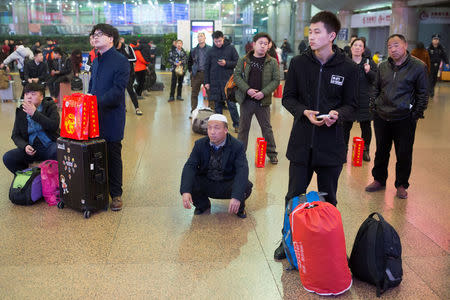 People watch the CCTV Spring Festival Gala TV show on a screen at the Beijing West train station in Beijing, China, January 15, 2018. REUTERS/Thomas Peter