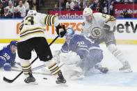 Toronto Maple Leafs goaltender Joseph Woll (60) makes a save as Boston Bruins' Brad Marchand (63) and Charlie Coyle (13) look for a rebound during third-period action in Game 6 of an NHL hockey Stanley Cup first-round playoff series in Toronto, Thursday, May 2, 2024. (Nathan Denette/The Canadian Press via AP)