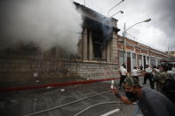 Clouds of smoke shoot out from the Congress building after protesters set a part of it on fire, in Guatemala City, Saturday, Nov. 21, 2020. Hundreds of protesters were protesting in various parts of the country Saturday against Guatemalan President Alejandro Giammattei and members of Congress for the approval of the 2021 budget that reduced funds for education, health and the fight for human rights. (AP Photo/Moises Castillo)