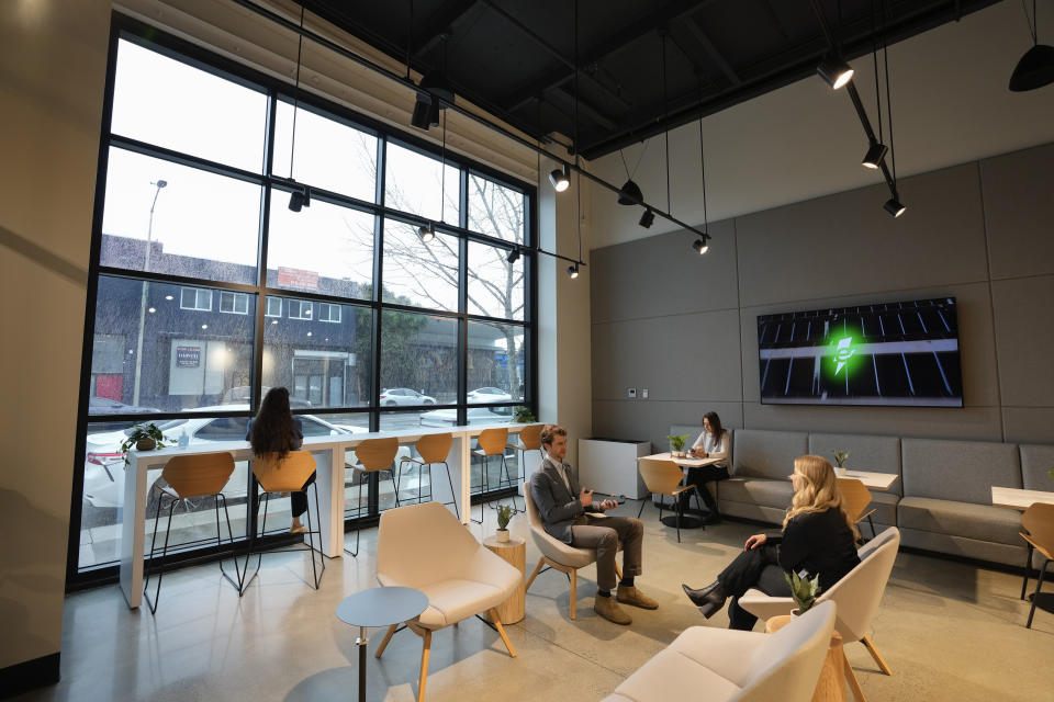 People sit in a waiting lounge at the new Electrify America indoor electric vehicle charging station in San Francisco, Wednesday, Feb. 7, 2024. Electrify America, Tesla, Mercedes and other charging networks are starting to build nicer spots for people to fill up their electric vehicles, knowing they'll be there for a lot longer than people spend at gas stations. (AP Photo/Eric Risberg)