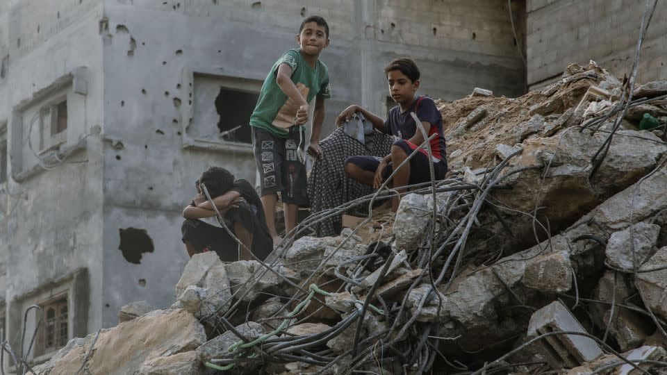 Three children in the rubble of ruined buildings that were destroyed by airstrikes in Gaza on October 25, 2023. - Youssef Alzanoun/Middle East Images/AFP/Getty Images