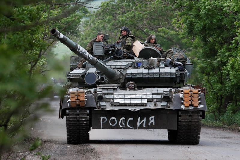 Service members of pro-Russian troops drive a tank in the Donetsk Region