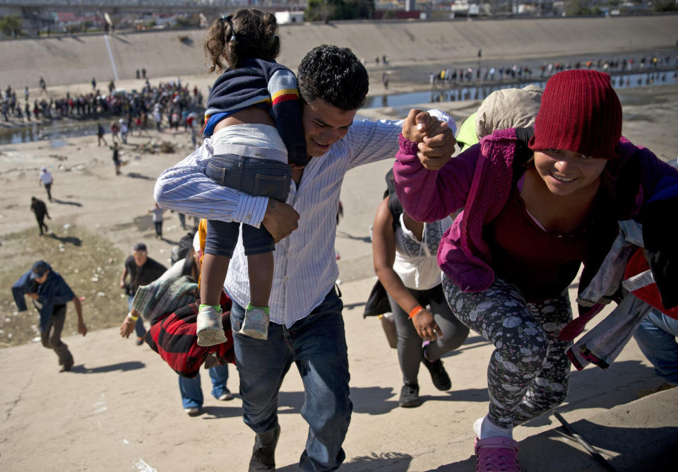 FILE - In this Nov. 25, 2018 file photo, migrants walk up a riverbank at the Mexico-U.S. border after getting past a line of Mexican police at the Chaparral border crossing in Tijuana, Mexico, as they try to reach the U.S. A San Diego TV station says the U.S. government ran an operation to screen journalists, activists and others while investigating last year's migrant caravan from Mexico. KNSD-TV says documents leaked by a Homeland Security source show a January database listing at least 10 journalists, seven of them U.S. citizens, as warranting secondary screening at U.S. points of entry. (AP Photo/Ramon Espinosa, File)