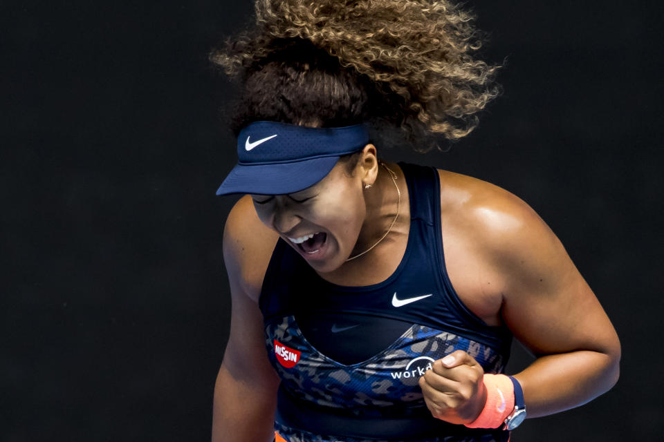 Naomi Osaka pumps her fist and yells to celebrate.