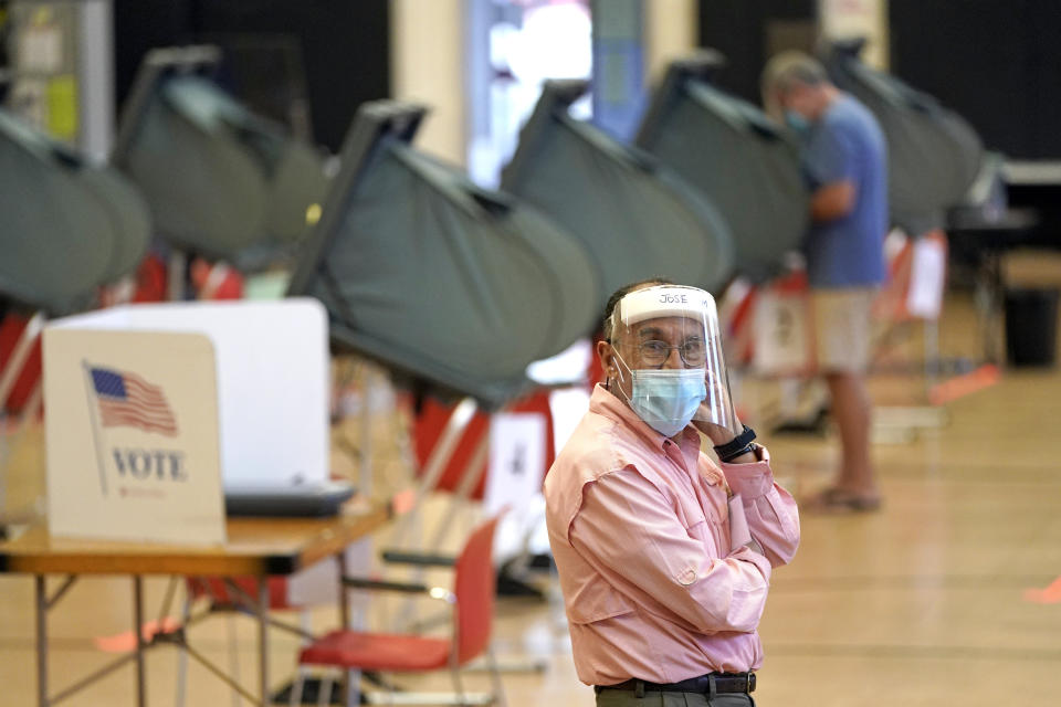 Harris County election clerk Jose Mendoza watches over voting booths, Monday, June 29, 2020, in Houston. Early voting for the Texas primary runoffs began Monday. (AP Photo/David J. Phillip)