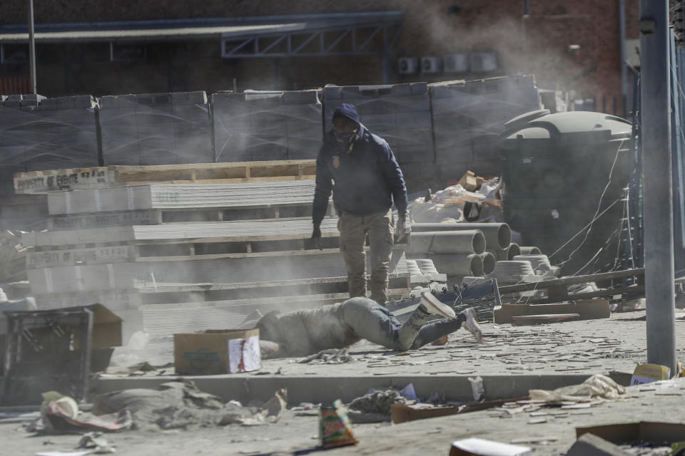 A police officer stops a man running away inside a shopping mall in Vosloorus, east of Johannesburg, South Africa, Wednesday July 14, 2021. South Africa's rioting continued Wednesday as police and the military struggle to quell the violence in Gauteng and KwaZulu-Natal provinces. The violence started in various parts of KwaZulu-Natal last week when Zuma began serving a 15-month sentence for contempt of court. (AP Photo/Themba Hadebe)