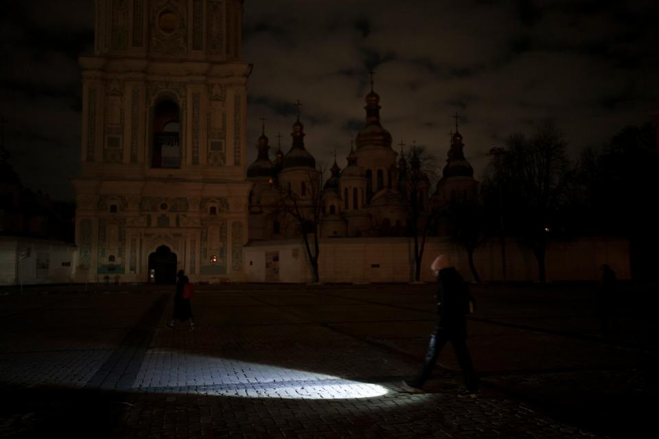 Russia’s shelling of Ukraine caused power outages across the country. Here a woman is walking with a torch during the blackout. (Copyright 2022 The Associated Press. All rights reserved.)