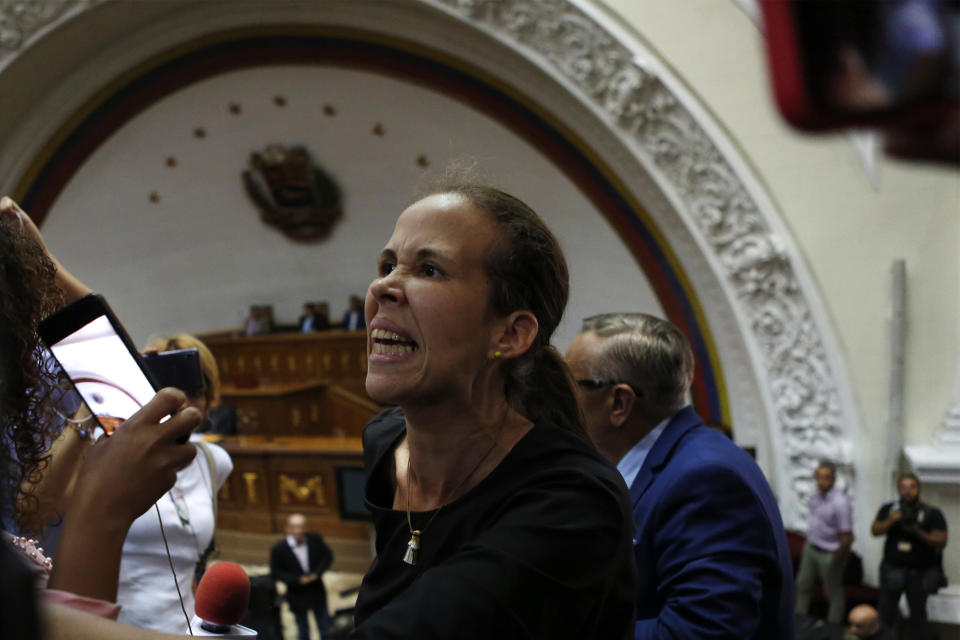 Opposition lawmaker Manuela Bolivar yells against former opposition ally, lawmaker Luis Parra, who is seated at the legislature president's desk, during a session at the National Assembly in Caracas, Venezuela, Tuesday, Jan. 7, 2020. Parra, a former opposition ally, declared himself the National Assembly’s leader on Sunday, then today opposition leader Juan Guaidó and opposition lawmakers pushed their way into the legislative building and swore-in Guaido as president of the legislature. (AP Photo/Andrea Hernandez Briceño)