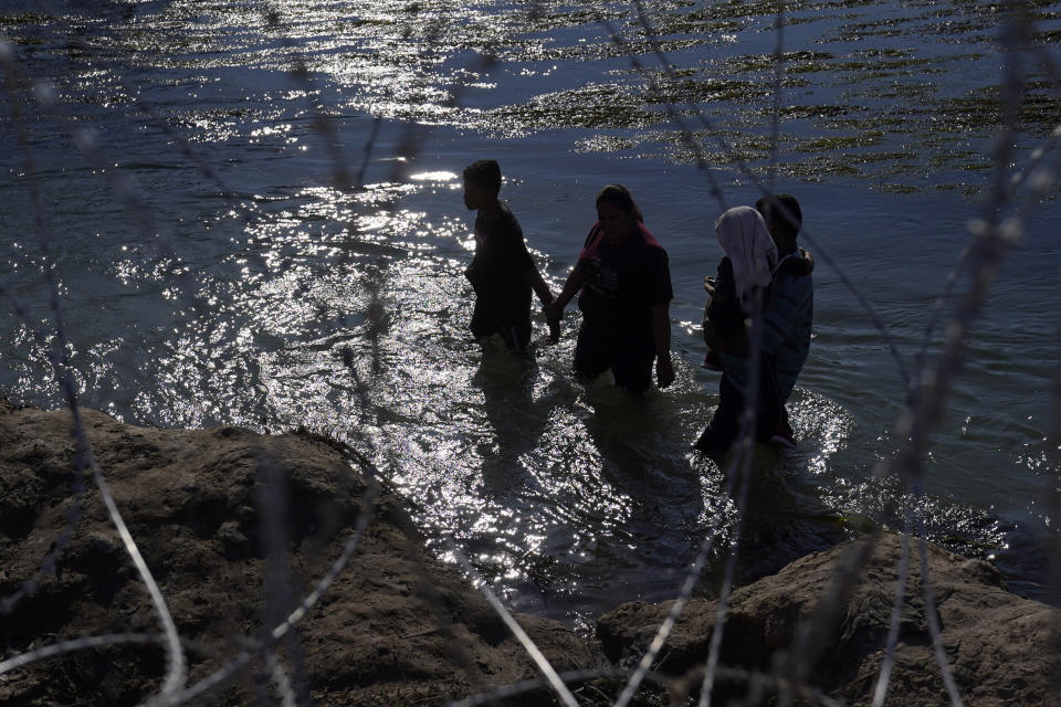 Migrants who crossed the Rio Grande from Mexico to the U.S. seek a way to pass through concertina wire, Friday, Sept. 22, 2023, in Eagle Pass, Texas. (AP Photo/Eric Gay)