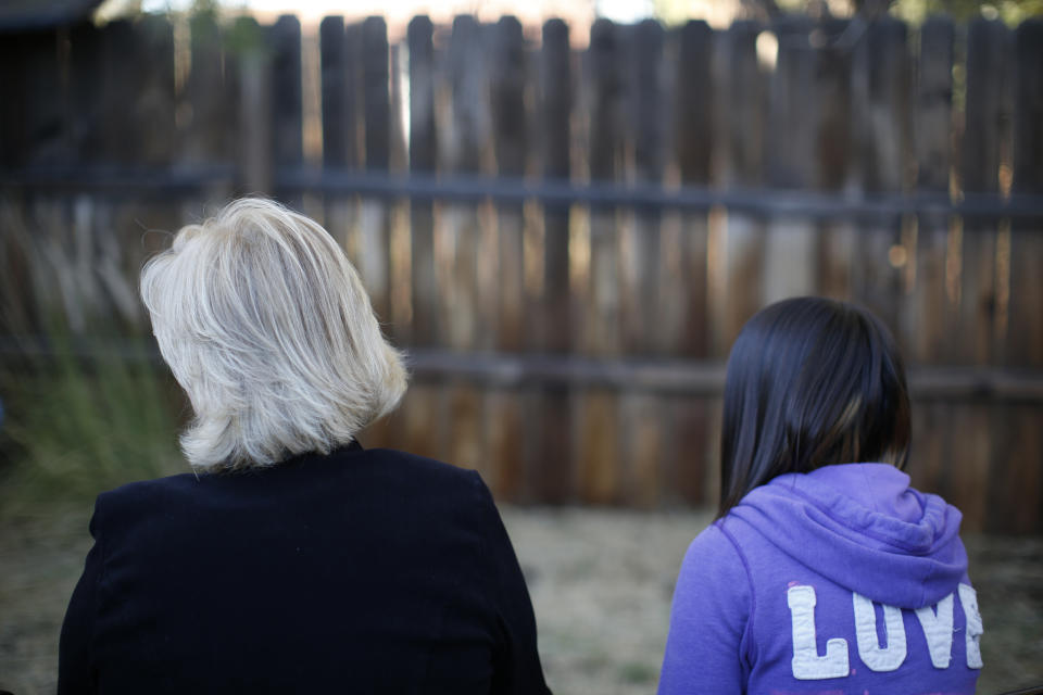FILE- MJ and her adoptive mother sit for an interview in Sierra Vista, Ariz., Oct. 27, 2021. State authorities placed MJ in foster care after learning that her father, the late Paul Adams, sexually assaulted her and posted video of the assaults on the Internet. (AP Photo/Dario Lopez-Mills, File)