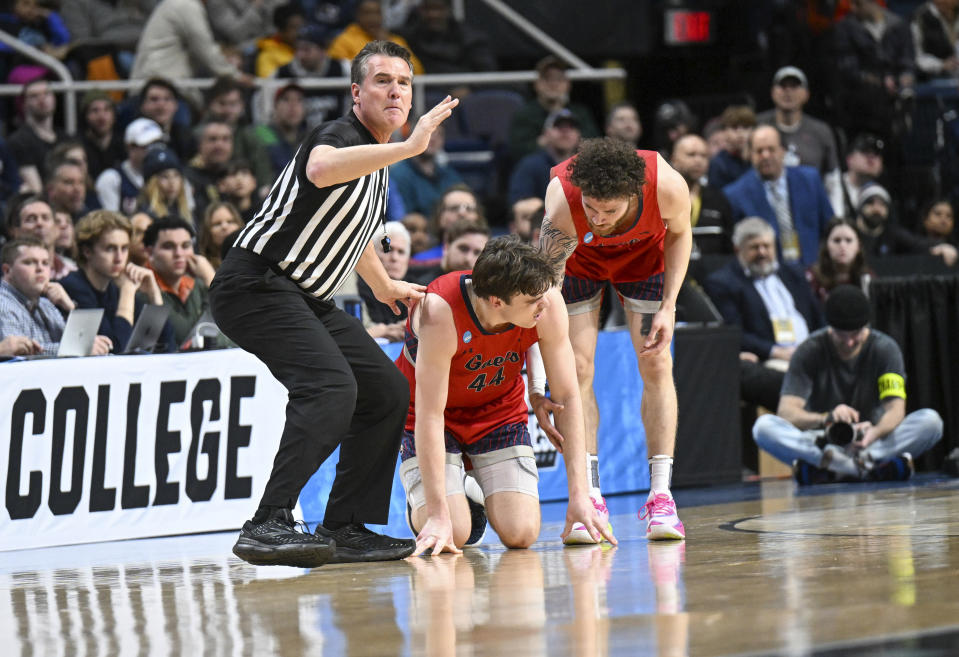 A official signals the bench that Saint Mary's guard Alex Ducas (44) is injured as Logan Johnson (0) looks to help him up during the first half of the team's second-round college basketball game against UConn in the men's NCAA Tournament on Sunday, March 19, 2023, in Albany, N.Y. (AP Photo/Hans Pennink)