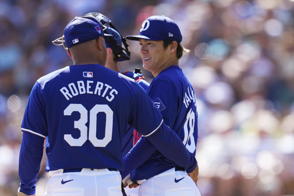 Los Angeles Dodgers manager Dave Roberts (30) talks with starting pitcher Yoshinobu Yamamoto, right, of Japan, as Yamamoto is removed during the fifth inning of the team's spring training baseball game against the Seattle Mariners on Wednesday, March 13, 2024, in Phoenix. (AP Photo/Ross D. Franklin)
