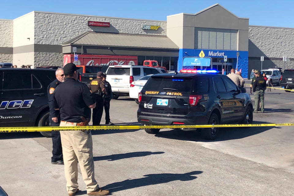 Law enforcement work the scene where two men and a woman were fatally shot Monday, Nov. 18, 2019, outside a Walmart store in Duncan, Okla. Two victims were shot inside a car and the third was in the parking lot outside the store in Duncan, Police Chief Danny Ford said. (AP Photo/Sean Murphy)