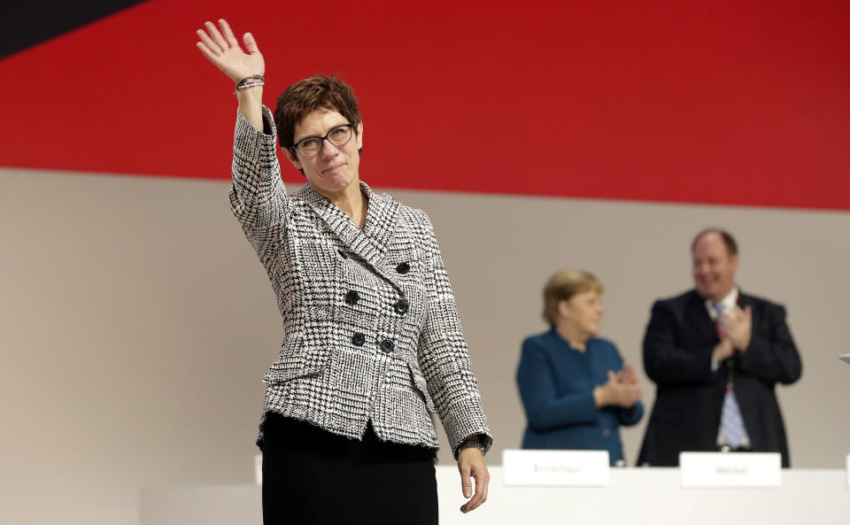 Newly elected CDU chairwoman Annegret Kramp-Karrenbauer, left, waves during the party convention of the Christian Democratic Party CDU in Hamburg, Germany, Friday, Dec. 7, 2018, after German Chancellor Angela Merkel didn't run again for party chairmanship after more than 18 years at the helm of the party. (AP Photo/Michael Sohn)