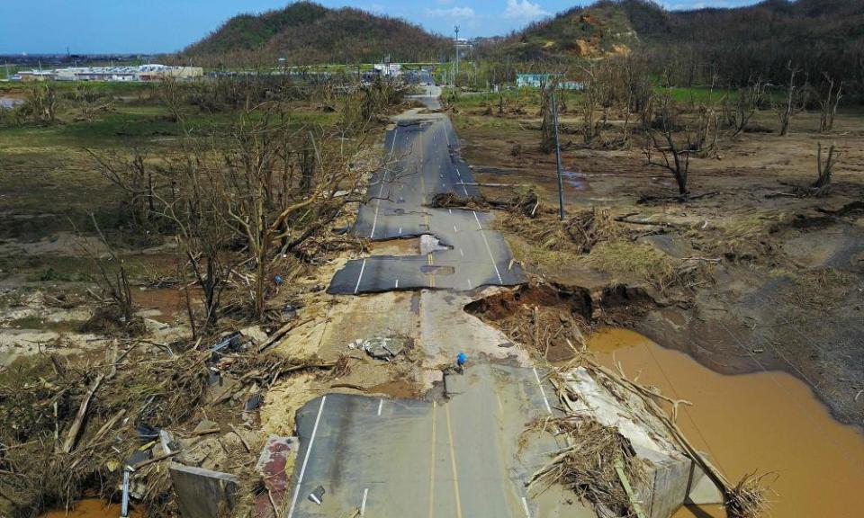 A man rides his bicycle through a damaged road in Toa Alta, west of San Juan, Puerto Rico