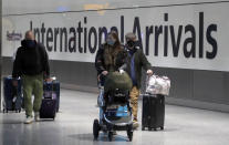 Travellers arrive at Heathrow Airport in London, Sunday, Jan. 17, 2021. The UK will close all travel corridors from Monday morning to protect against the coronavirus with travellers entering the country from overseas are required to have proof of a negative Covid test. (AP Photo/Frank Augstein)