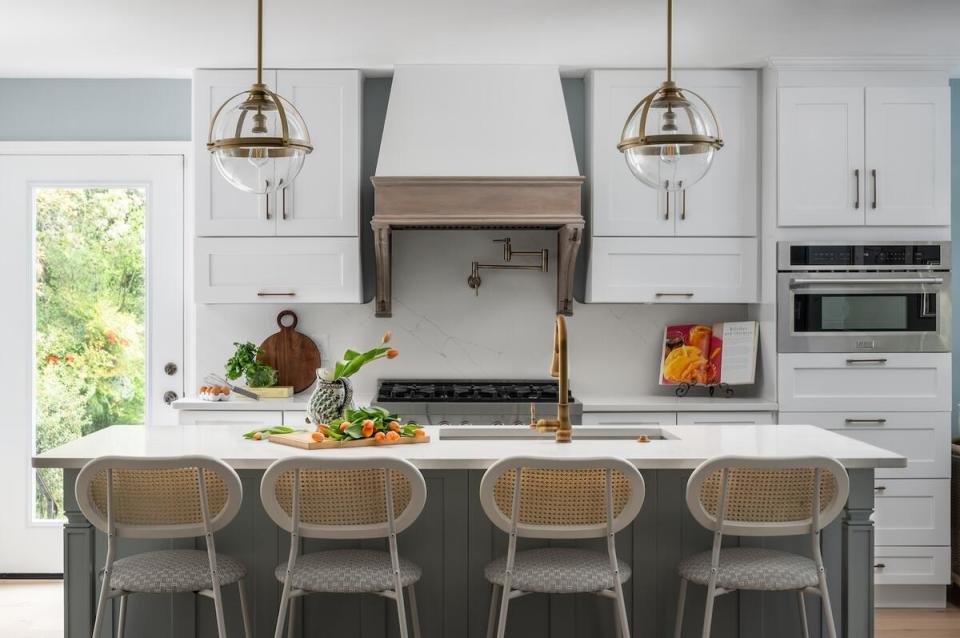 A crisp kitchen in white and pale gray features statement lighting and ample storage