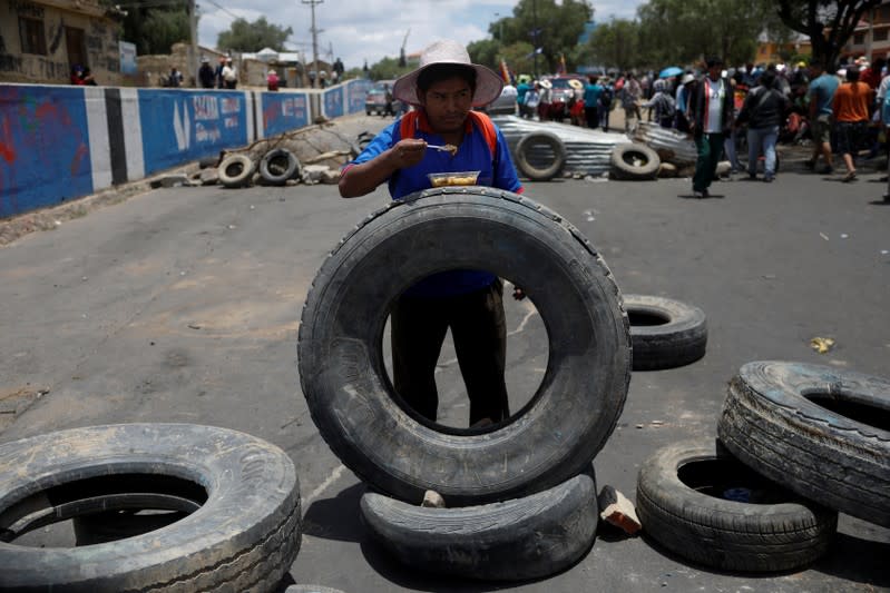 A man have lunch at a barricade as fellow coca farmers and supporters of Bolivia's ousted President Evo Morales stage a blockade of an entrance to Sacaba