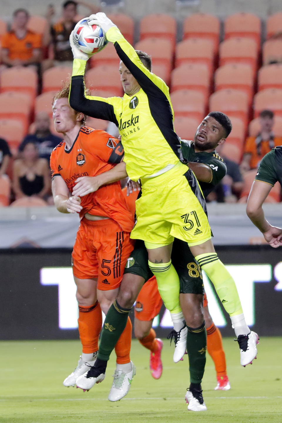 Portland Timbers goalkeeper Aljaz Ivacic (31) makes the save over Houston Dynamo defender Tim Parker (5) and defender Zac McGraw, right, during the second half of an MLS soccer match Wednesday, June 23, 2021, in Houston. (AP Photo/Michael Wyke)