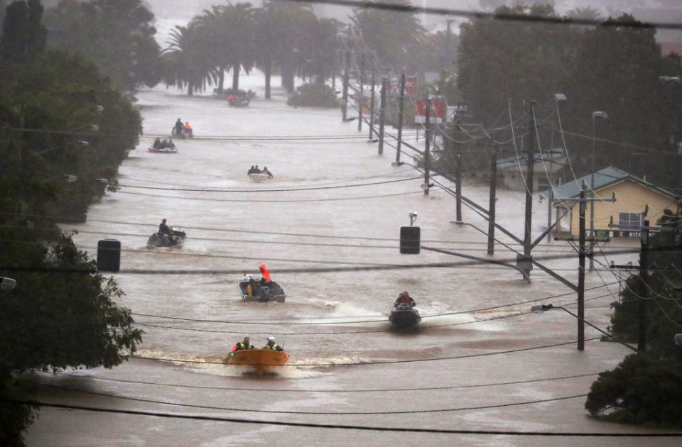 People use small boats to travel through flood water in Lismore (AP)