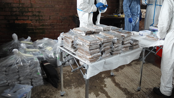 Table and floor piled high with blocks of brown class A drugs