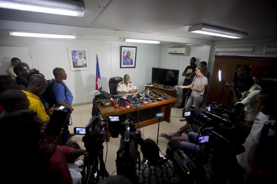 In this Dec. 3, 2018 photo, police officer Garry Derosier presents to the press seized guns, bullets and other items taken from arrested gang members during a national police bust of a gang's base near La Saline slum of Port-au-Prince, Haiti after a massacre in the slum. There are at least two police sub-stations in La Saline and the surrounding area, but witnesses said neither station sent officers to intervene as black-clad men went door to door pulling young men from their homes and killing them, often with a single shot to the head. (AP Photo/Dieu Nalio Chery)