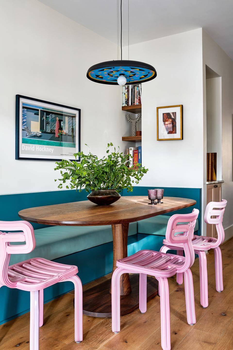 Who would have thought that the bubblegum pink chairs in the dining room were made of recycled plastic—or more precisely, from the upcycled plastic interiors of a standard-size fridge? Zoë, that’s who. She brought in the Chubby chairs by Kooij both as a conversation starter and as a playful counterpoint to the Fajen & Brown custom banquette outfitted in Kravet’s Rock Solid faux leather in the shade Patina. “They’re much sturdier than they look,” says one husband. The restraint of Loewen Design Studio’s Walnut Jarvis Racetrack Oval pedestal table offsets the surrounding palette. Artworks include a David Hockney lithograph (left) and an autographed portrait of Anna Nicole Smith. The pendant is the Alfred design by Always Welcome.