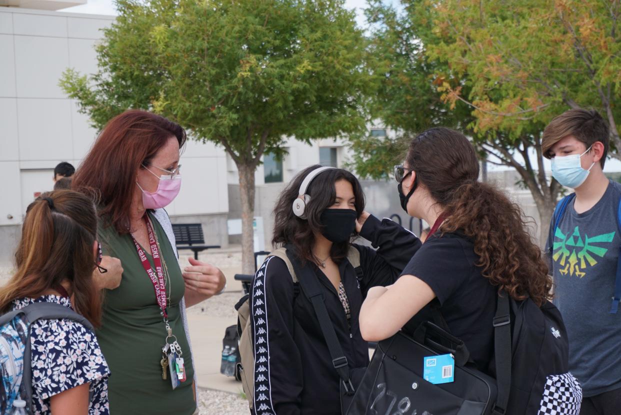 Carlsbad Early College High School teacher Marta Donaghe talks to students about social distancing as they leave school for the day.