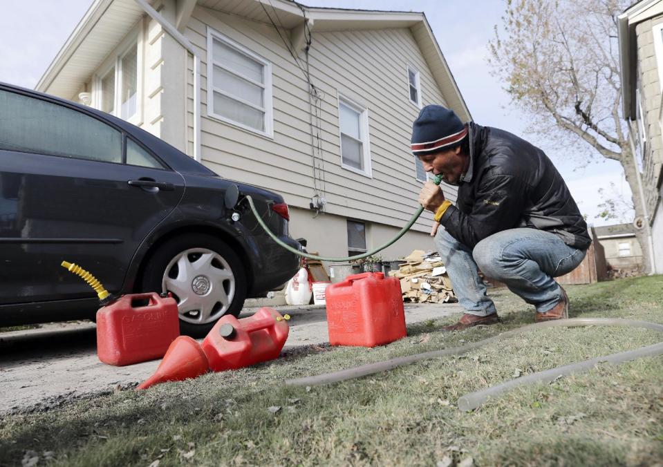 Chris Zaturoski uses a garden hose to attempt to siphon gasoline from his car to use in a generator at his house which is without power in the wake of superstorm Sandy on Thursday, Nov. 1, 2012, in Little Ferry, N.J. The hose was too big to fit into the gas tank of the car. New Jersey residents across the state were urged to conserve water. At least 1.7 million customers remained without electricity. (AP Photo/Mike Groll)