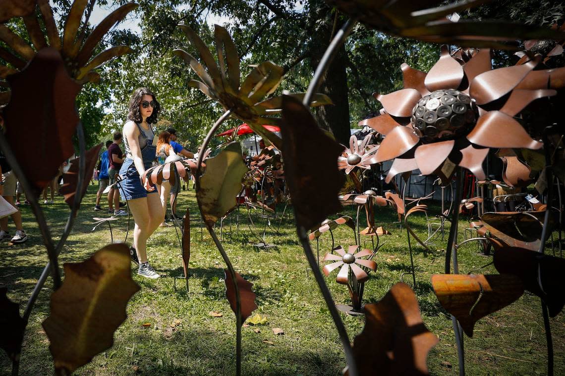 Amanda Judy examines handmade metal garden sculptures at one of the dozens of booths at last years Woodland Art Fair at Woodland Park.