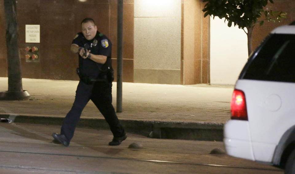 A Dallas police officer aims his gun during the chaos after a sniper ambushed officers in downtown Dallas on Thursday. (AP Photo/LM Otero)