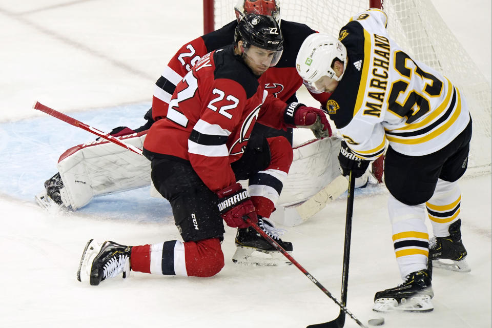 New Jersey Devils defenseman Ryan Murray (22) tries to keep Boston Bruins left wing Brad Marchand (63) from the puck in front of Devils goaltender Mackenzie Blackwood (29) during the first period of an NHL hockey game, Tuesday, May 4, 2021, in Newark, N.J. (AP Photo/Kathy Willens)