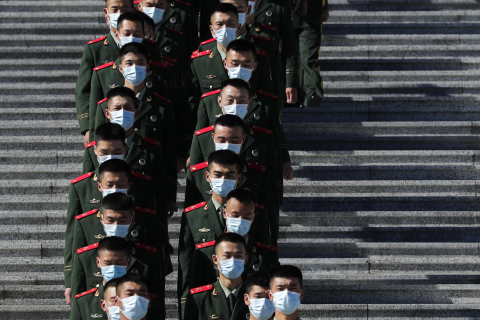 Chinese paramilitary policemen wearing face masks to help curb the spread of the coronavirus march down a staircase outside the Great Hall of the People after attending the commemorating conference on the 70th anniversary of China's entry into the 1950-53 Korean War, in Beijing Friday, Oct. 23, 2020. (AP Photo/Andy Wong)