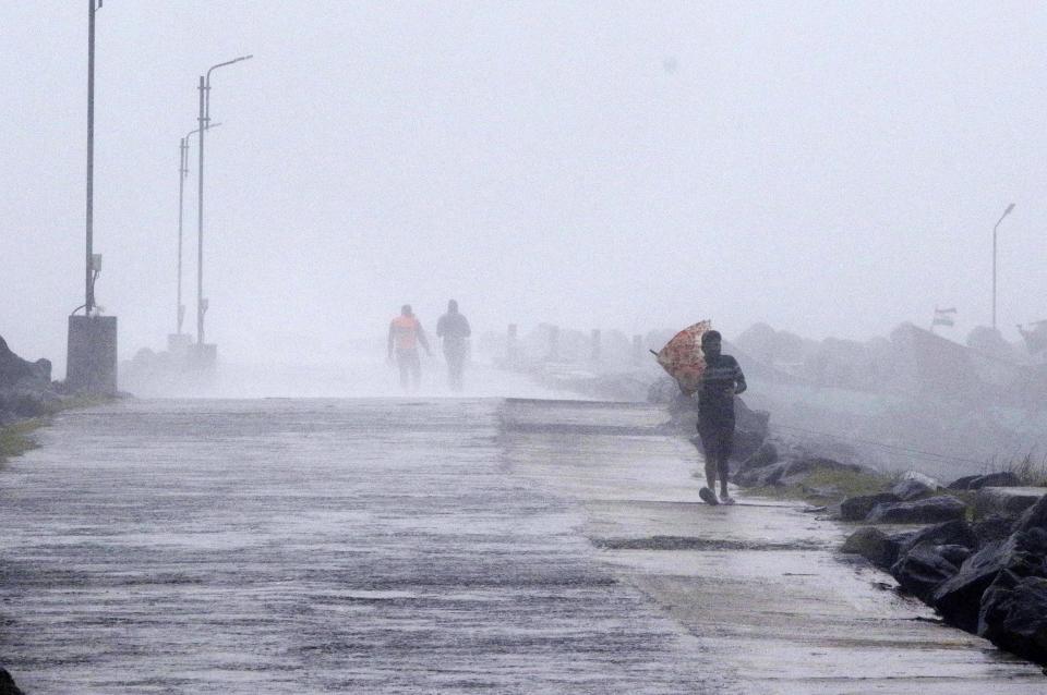 A man tries to hold his umbrella against strong winds at the Kasimedu Harbor on the Bay of Bengal coast in Chennai, India, Wednesday, Nov.25, 2020. India’s southern state of Tamil Nadu is bracing for Cyclone Nivar that is expected to make landfall on Wednesday. The state authorities have issued an alert and asked people living in low-lying and flood-prone areas to move to safer places. (AP Photo/R. Parthibhan)