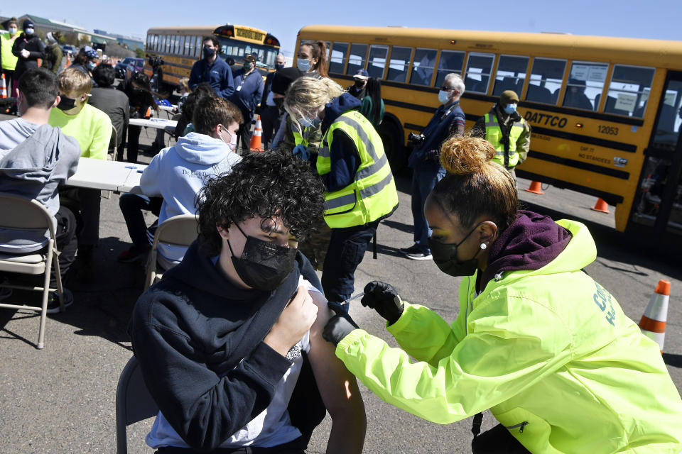 FILE - In this April 26, 2021, file photo, CREC Academy of Aerospace and Engineering sophomore Brian Acevedo, 16, receives a COVID-19 vaccine from nurse Myra Glass, of East Hartford, during a mass vaccination site at Pratt & Whitney Runway in East Hartford, Conn. Teams of experts are projecting COVID-19's toll on the U.S. will fall sharply by the end of July, according to research released by the government Wednesday, May 5. (AP Photo/Jessica Hill, File)