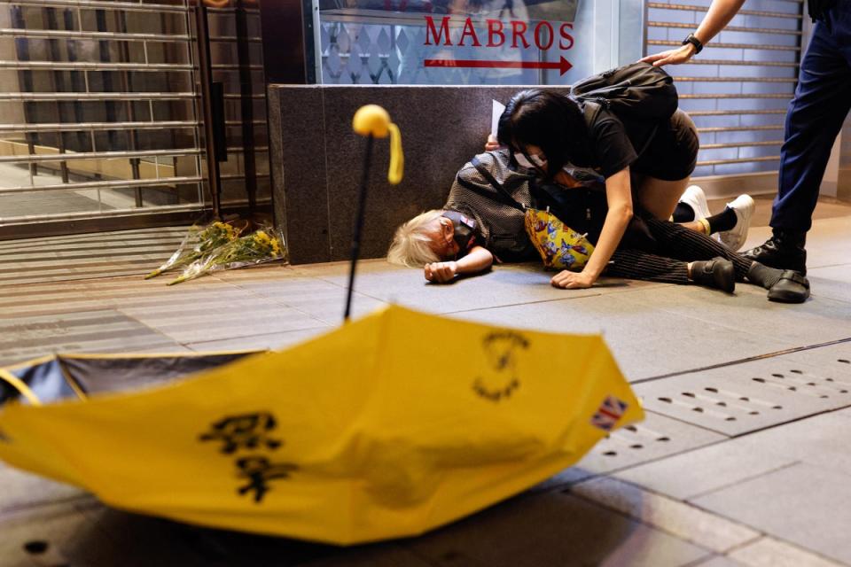 A protester lies on the ground in Hong Kong after being pushed during demonstrations against Covid on mainland China (Reuters)