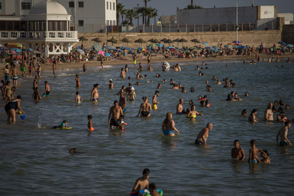 Bathers enjoy the beach in Cadiz, south of Spain, on Friday, July 24, 2020. With the coronavirus rebounding in parts of Spain, it appears that several regions have not adequately prepared to trace new infections in what was supposed to be an early detection system to prevent a new cascade of cases. (AP Photo/Emilio Morenatti)