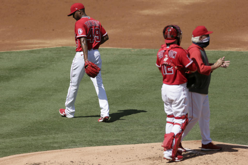 Los Angeles Angels starting pitcher Julio Teheran, left, walks away from the mound after manager Joe Maddon, right, pulls him the second inning of a baseball game against the Texas Rangers in Anaheim, Calif., Sunday, Sept. 20, 2020. Catcher Anthony Bemboom is center. (AP Photo/Alex Gallardo)