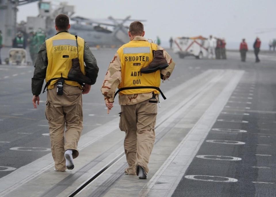 Lt. Nicholas Woodworth and Robert Wilkerson prepare to shoot their boots off the flight deck of USS Carl Vinson