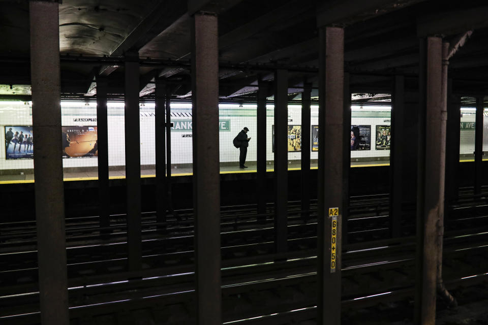 A solitary subway customer stands on an empty platform in the morning hours as COVID-19 concerns drives down public gatherings, Thursday, March 19, 2020, in New York. As of Sunday, nearly 2,000 people with the virus have been hospitalized in the state of New York and 114 have died, officials said. More than 15,000 have tested positive statewide, including 9,000 in New York City. (AP Photo/John Minchillo)