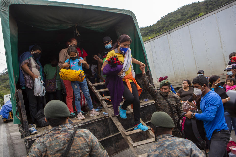 A Honduran migrant woman is helped off a Guatemalan army truck after being returned to El Florido, Guatemala, one of the border points between Guatemala and Honduras, Tuesday, Jan. 19, 2021. A once large caravan of Honduran migrants that pushed its way into Guatemala last week had dissipated by Tuesday in the face of Guatemalan security forces. (AP Photo/Oliver de Ros)