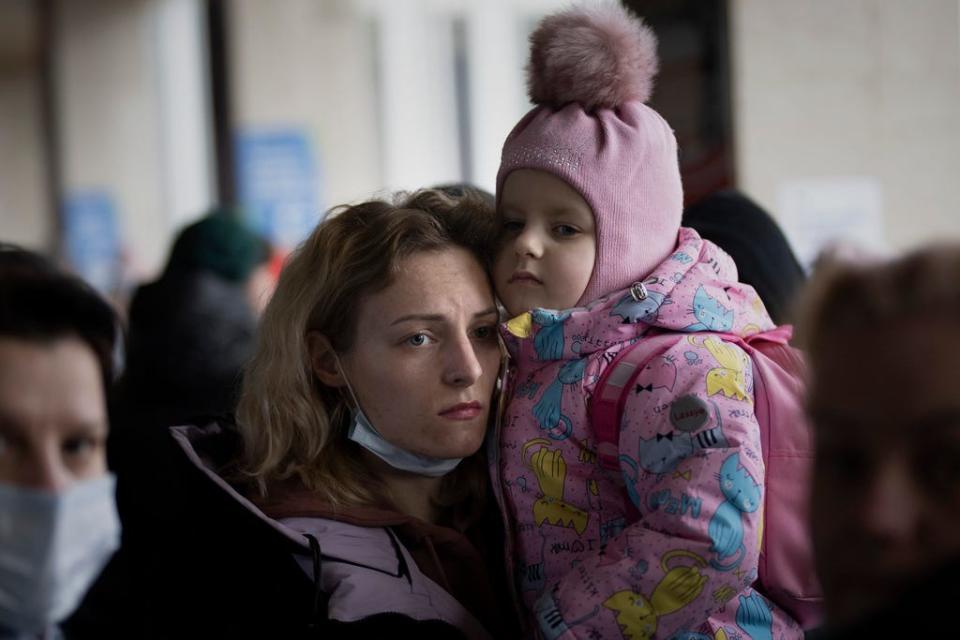 A woman holds her daughter as they try to get on a train at the Kyiv station, Ukraine, Friday, March 4. 2022.
