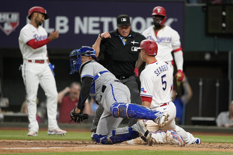 Kansas City Royals catcher Salvador Perez, front left, and Texas Rangers' Corey Seager (5) look on as umpire Cory Blaser, center rear, calls Seager out in the third inning of a baseball game, April 10, 2023, in Arlington, Texas. Seager was attempting to score on a Nathaniel Lowe double. (AP Photo/Tony Gutierrez)