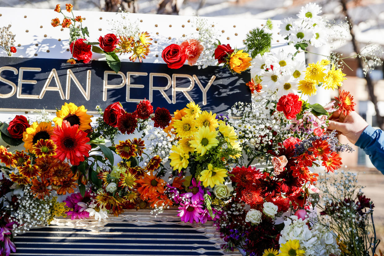 Ross Brown places flowers on a memorial for three slain University of Virginia football players on Saturday, Nov. 19, 2022, at John Paul Jones Arena on the university's campus in Charlottesville, Va. On Sunday, Nov. 13, University of Virginia football players Devin Chandler, Lavel Davis Jr. and D'Sean Perry were shot and killed by a teammate following a school field trip to Washington. (Shaban Athuman/Richmond Times-Dispatch via AP)