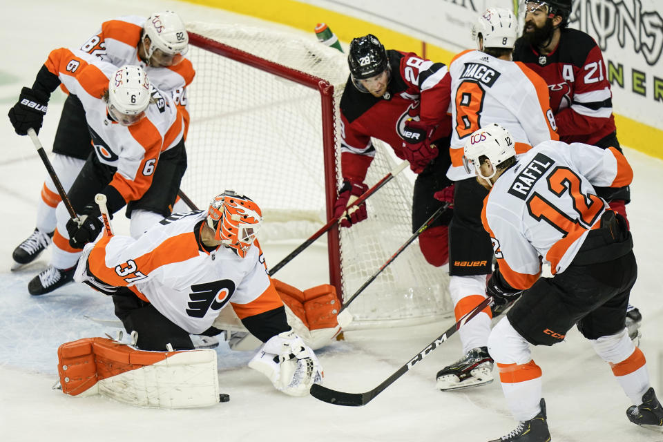 Philadelphia Flyers goaltender Brian Elliott (37) stops a shot on goal by New Jersey Devils' Damon Severson (28) as Philadelphia Flyers' Robert Hagg (8), Michael Raffl (12), and Ivan Provorov (9) defend during the second period of an NHL hockey game Tuesday, Jan. 26, 2021, in Newark, N.J. (AP Photo/Frank Franklin II)