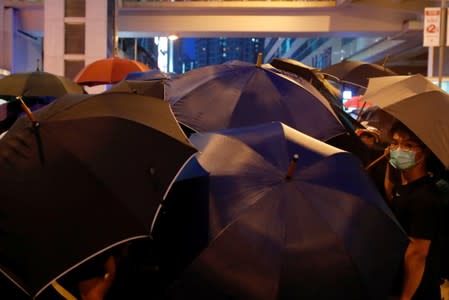 Protesters hold umbrellas to protect themselves from being pepper-sprayed after a march at Sheung Shui, Hong Kong