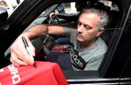 Jose Mourinho signs a Manchester United soccer shirt held out by a fan as he leaves his house in London, Britain, May 27, 2016. REUTERS/Toby Melville